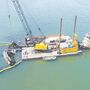 Aerial view of a barge and crane removing a derelict sailboat