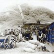 A historic black and white photo of grain threshing