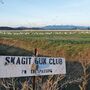 Skagit Valley Gun club sign with snow geese in field behind it.