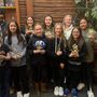 Girls soccer team standing with sportsmanship trophy.