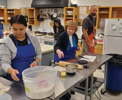 State Sen. Lisa Williams helping students in kitchen.