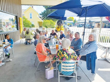 Women sit at an outdoor table to celebrate a birthday