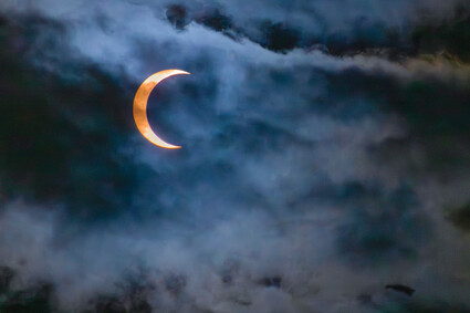 Photo of partial solar eclipse with clouds.