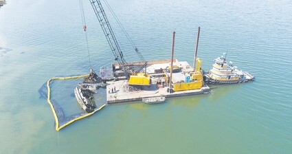 Aerial view of a barge and crane removing a derelict sailboat